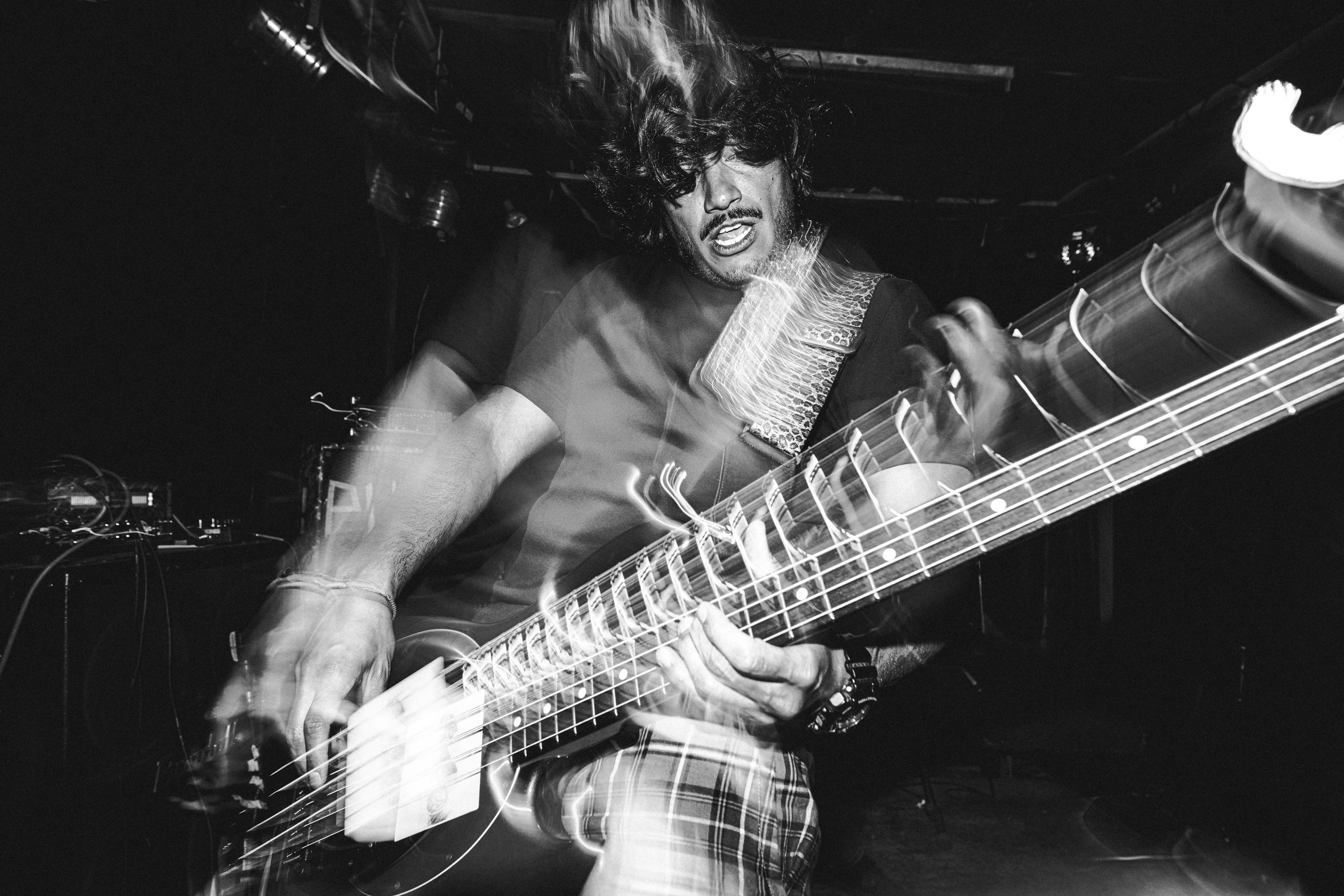Black and white photo of energetic bassist performing live with motion blur effects.